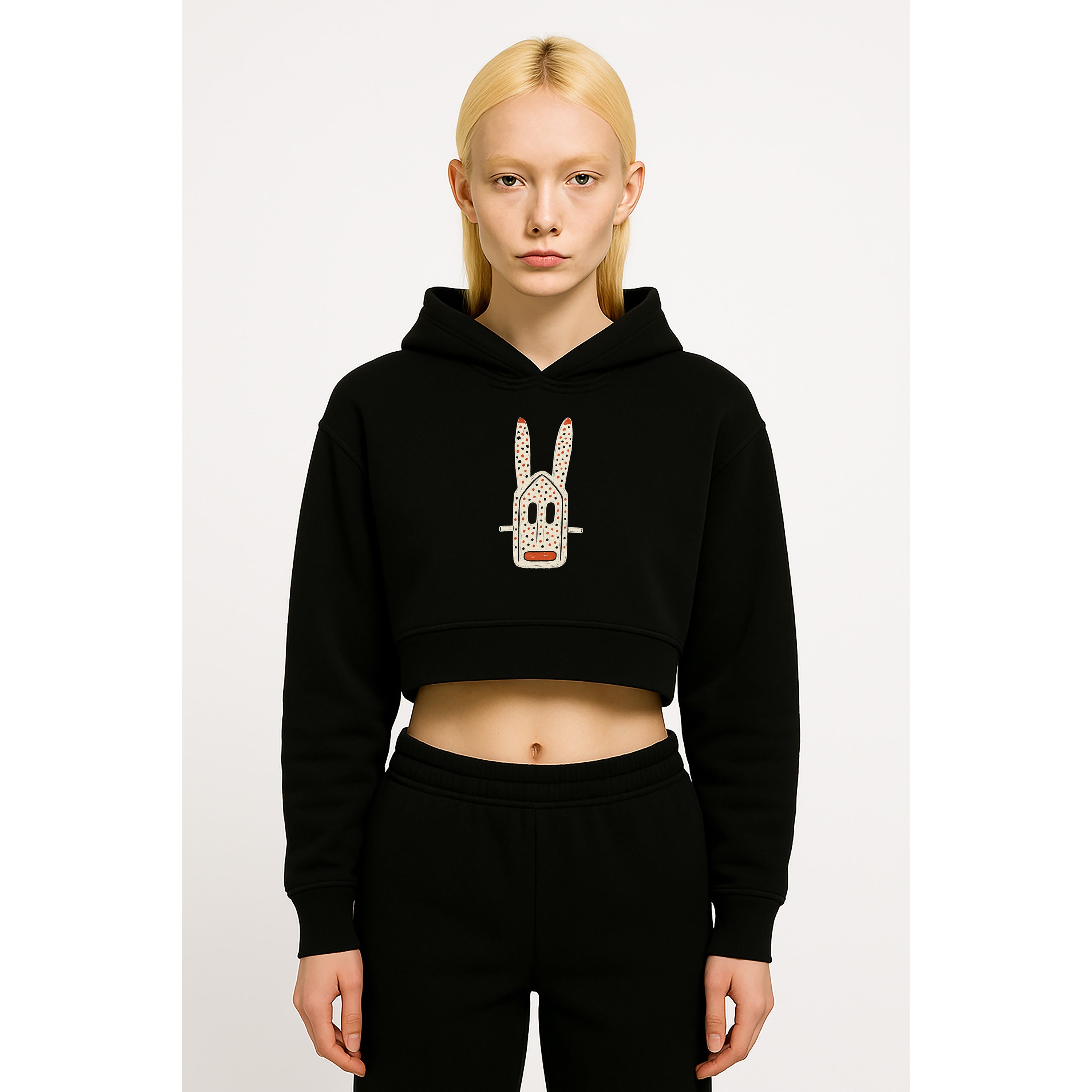 Model wears nomad_07 women’s Onyx cropped hoodie featuring Dogon Rabbit graphic inspired by Dogon masquerade and Japanese character art, front view