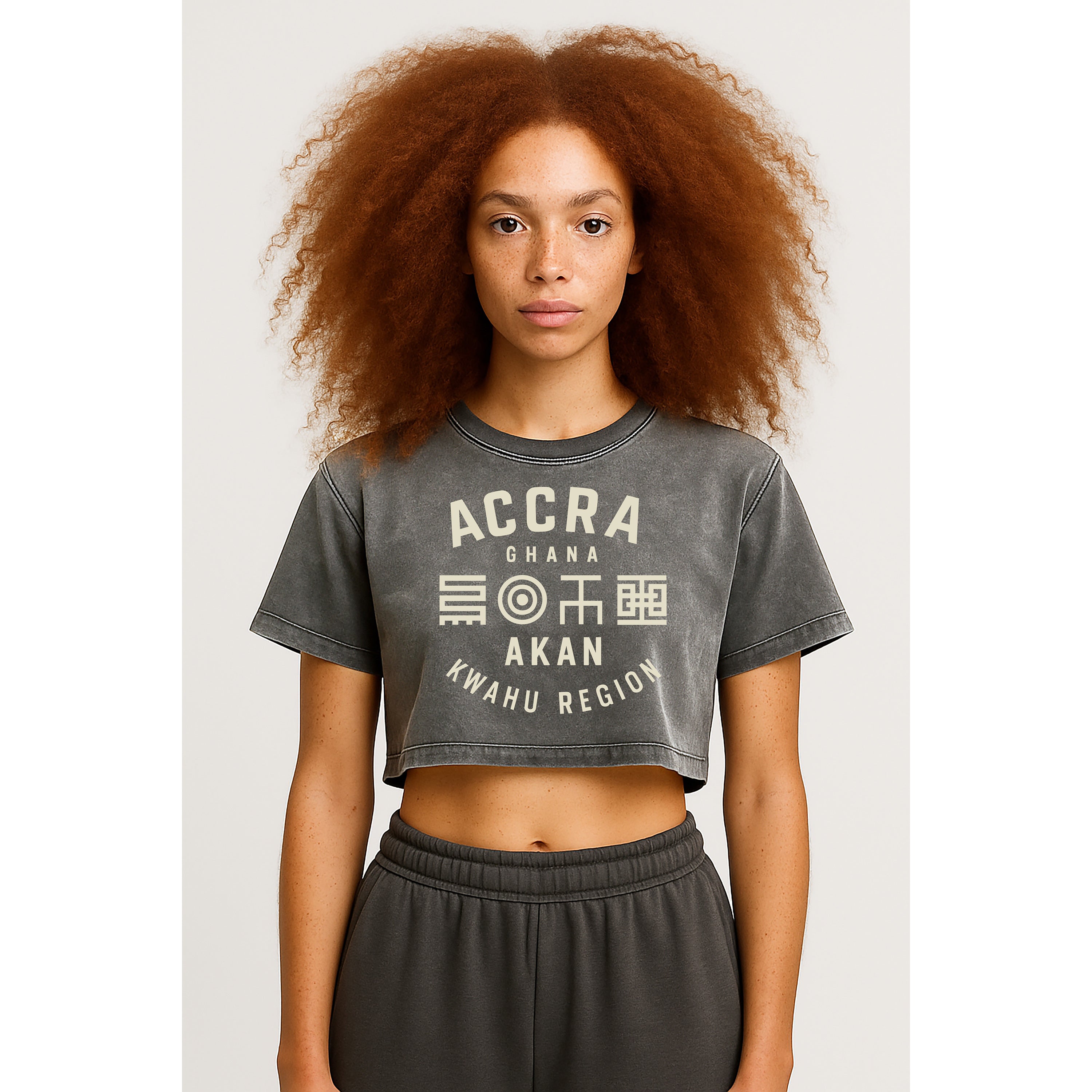 A model standing forward wears the nomad_07 women's cropped Solar Patina t-shirt in Ash Grey with Ghana Akan Script graphic front view