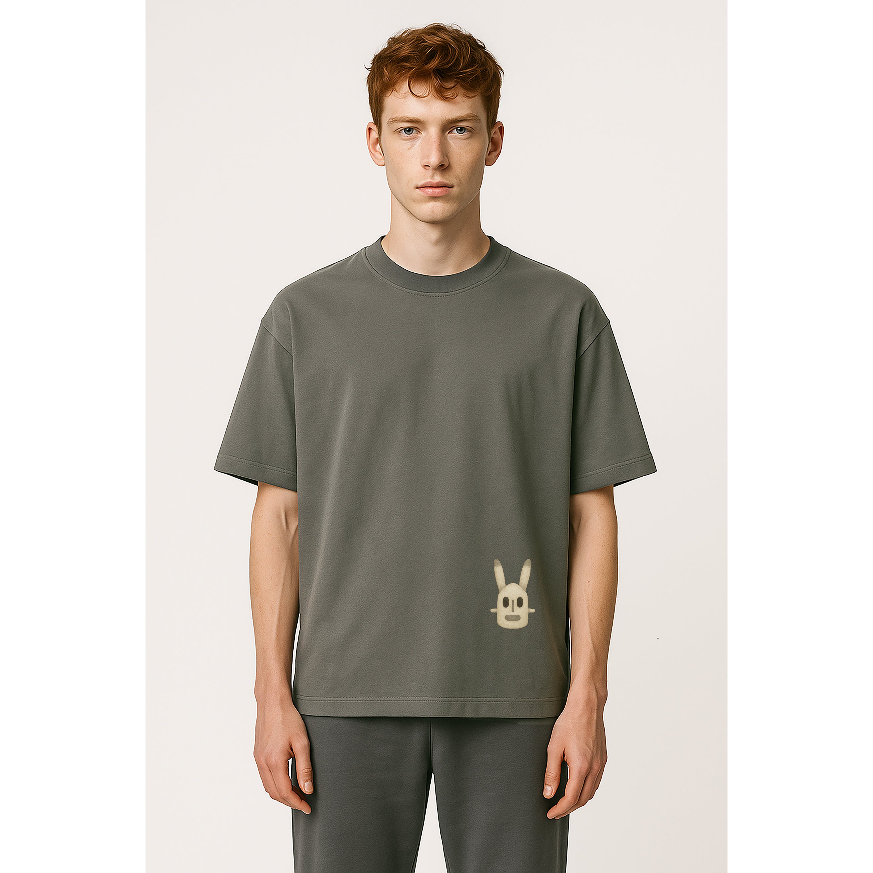 Man wears oversized heavyweight grey tee with Mali dogon rabbit phantom graphic at lower hem on solid background